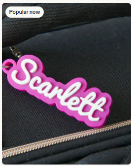 Pink layered acrylic name tag shown attached to a black backpack